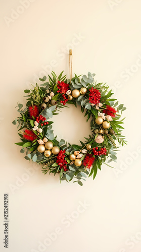 A beautifully decorated Christmas wreath hanging on a plain white wall Australian Christmas