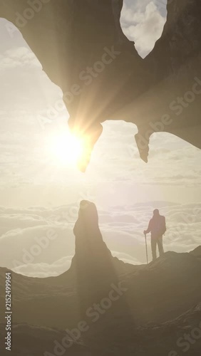 Adventurous Hiker on Mountain Peak Above Clouds with Sunrise Through Rock Arch