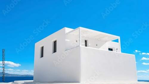 Minimalist white house with flat roof on a sunny day overlooking blue ocean.