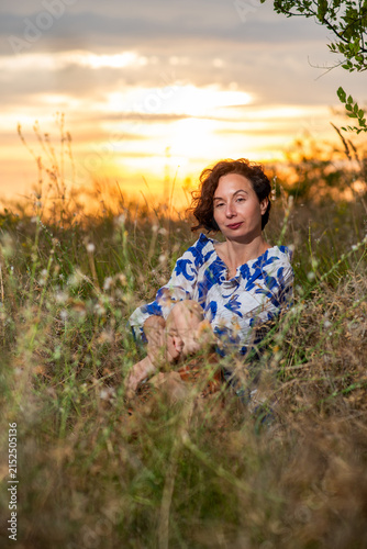 Woman Sitting in Meadow at Sunset