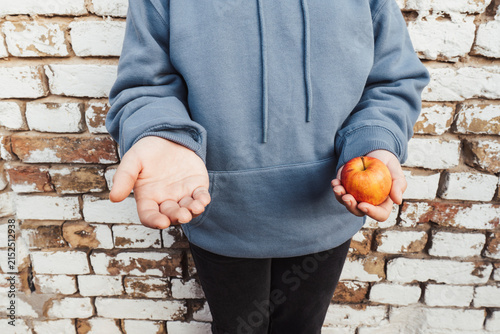 Foto Concept of poverty and hunger: a teenager in a hoodie holds one apple and offers