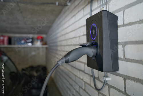 Foto close up of hand plugging electric vehicle charging cable into home wallbox char