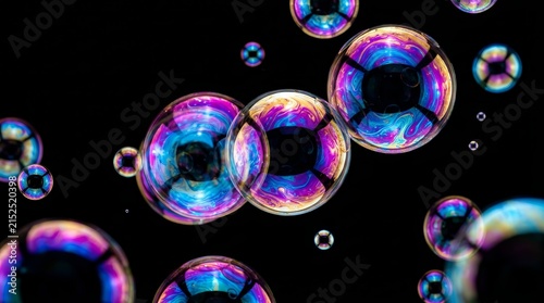 Colorful soap bubbles floating in the air against a dark background.