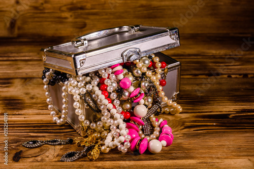 Aluminium case full of different jewelry on wooden table