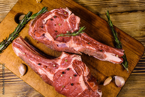 Raw ribeye steak, spices and rosemary on cutting board. Top view