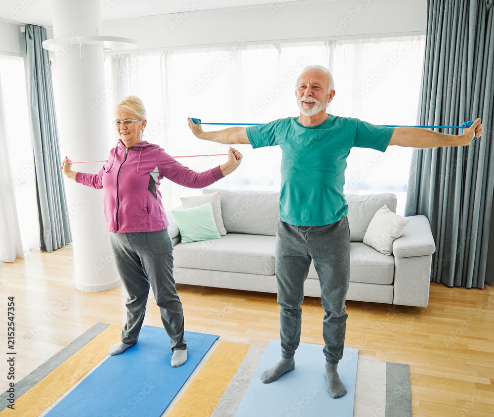 Fototapeta premium Senior couple exercise stretching resistance band at home, health care and active seniors concept