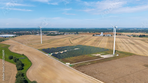 Aerial drone view of wind turbine and solar panel farm surrounded by agricultural fields – renewable energy landscape photo