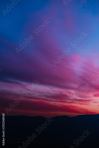 Vivid sunset over dark mountain silhouettes and desert hills in Joshua Tree National Park, California