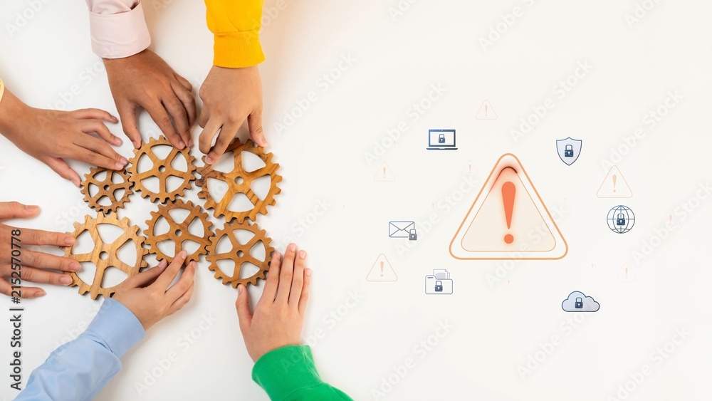 Obraz premium A diverse group of hands gathers around gears on a table, symbolizing teamwork and collaboration. A warning icon highlights communication and cybersecurity issues in today work environment. Raster