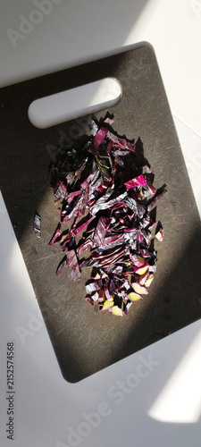 Chopping red cabbage on a black cutting board in a bright kitchen