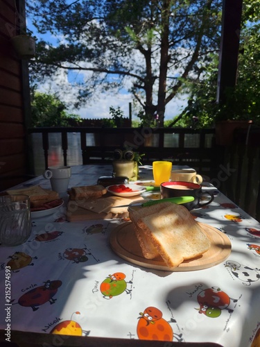 Rustic breakfast with toast, coffee, tea, cheese and fresh berries on a countryside veranda table