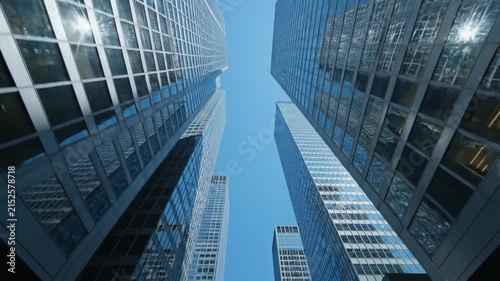 Modern Urban Perspective of Glass Skyscrapers Reflecting Blue Sky, Ideal for Corporate Backgrounds.