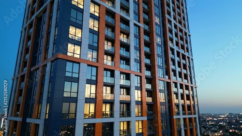 Modern Skyscraper Facade with Orange and Blue Panels at Dusk, Ideal for Real Estate Marketing.