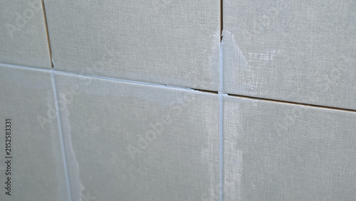 Worker using a rubber grout float to smooth grout between tiles. Carefully applying sealant to tiles joints. Workman hands smoothing caulk, using small tool to remove excess and create clean seam.