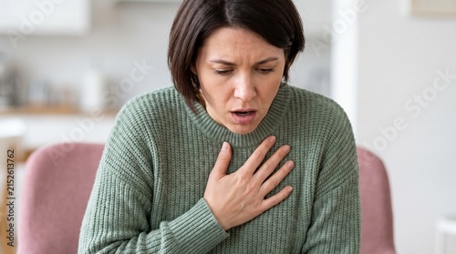 Unhealthy young woman holding chest suffering from pain or difficulty breathing at home