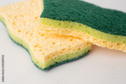 Two green and yellow kitchen sponges on white background.