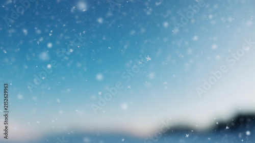 Falling snow flakes against a soft blue winter sky background for seasonal holiday design.