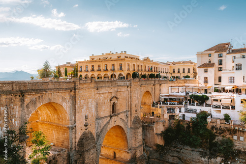 Iconic Puente Nuevo bridge connecting two parts of Ronda, showcasing historic architecture and buildings perched dramatically on the cliff edge under a clear sky in Andalucia, Spain