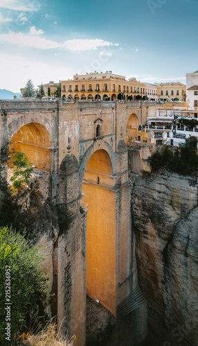 Puente Nuevo bridge connecting the old and new town of Ronda across the dramatic El Tajo gorge, featuring historic architecture and rugged natural landscape under a blue sky in Andalucia