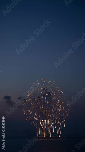 Bright golden fireworks exploding over a dark ocean during a late evening celebration