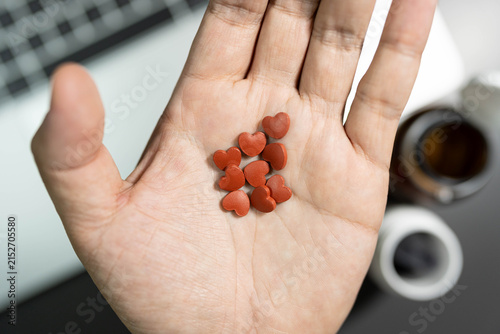 heart shaped pills over laptop workspace concept of heart care for overworked office employee. heart disease prevention, cardiovascular care, workplace stress, health supplements for overworked