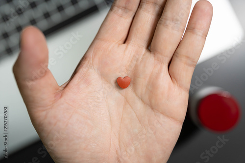 heart shaped pills over laptop workspace concept of heart care for overworked office employee. heart disease prevention, cardiovascular care, workplace stress, health supplements for overworked