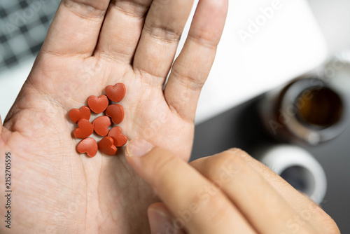 heart shaped pills over laptop workspace concept of heart care for overworked office employee. heart disease prevention, cardiovascular care, workplace stress, health supplements for overworked