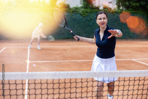 Foto Adult woman playing doubles tennis against opponent team on tennis court