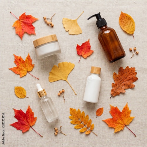Flat lay composition of natural skincare cosmetic bottles and autumn leaves on linen background, seasonal beauty routine and organic spa products