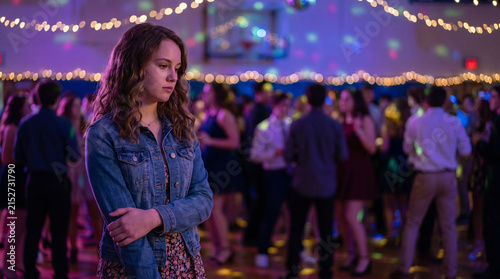 Sad teenage girl standing alone at high school prom