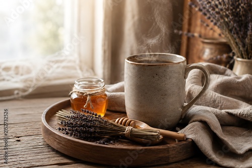 A steaming mug of herbal tea with a small jar of honey and lavender sprigs on a rustic wooden tray.
