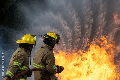 Obraz na płótnie Team of firefighter in fireproof clothe are using twirl fog watering hose to put