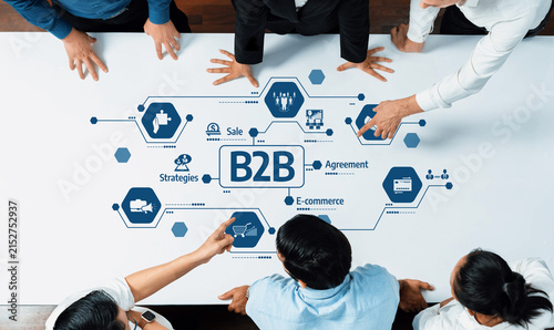 Картината върху платно A diverse group of professionals collaborates around a table, discussing strategies for B2B and e-commerce, emphasizing teamwork and innovative solutions in a modern setting