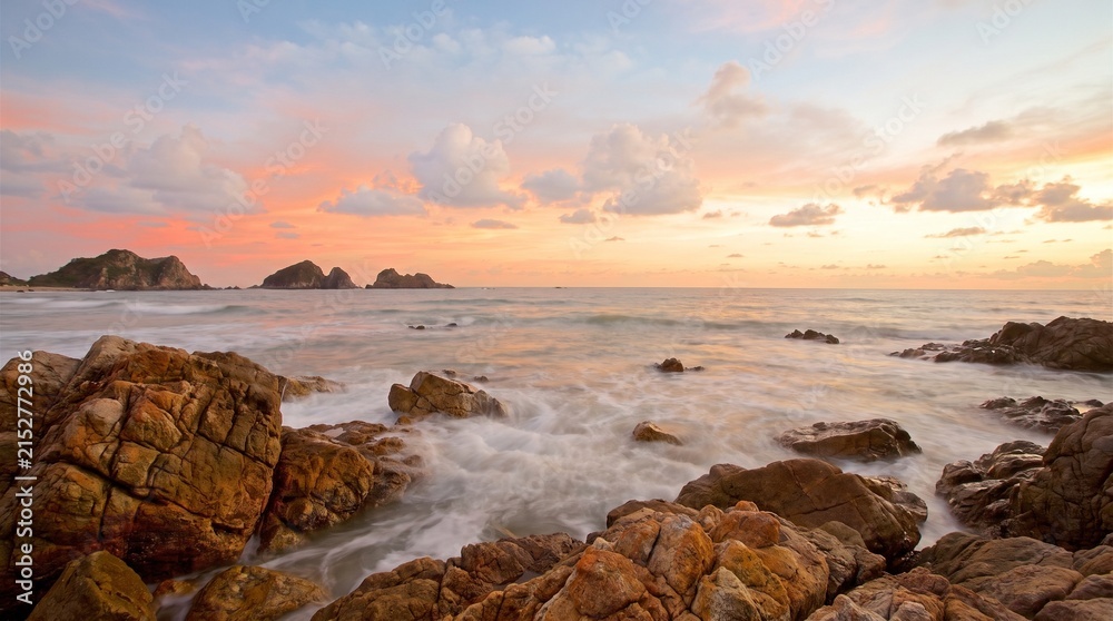Obraz premium Coastal landscape with rocky shoreline and sunset sky at golden hour