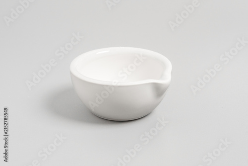 Bild auf Leinwand Clean studio shot of an empty white porcelain mortar bowl featuring a pouring spout, placed on a light grey background