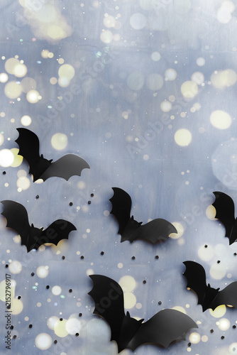 Silhouettes of flying black and dark grey bats on blue background with bokeh. Minimal and spooky holiday pattern for Halloween background, wallpaper, party invitations. Aesthetic top view, flat lay