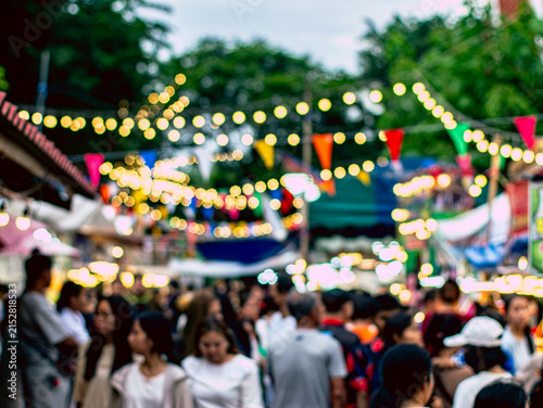 Blurred Crowd at Night Market with Bokeh String Lights and Colorful Flags