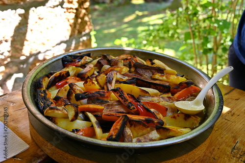 Potatoes and pork meat baked in roasting plate with carrot and pepper