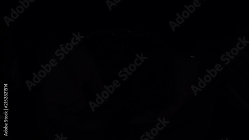 Handcuffs on hands under red and blue emergency vehicle lights.