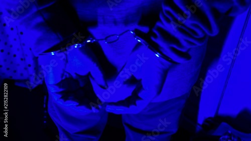 Handcuffs on hands under red and blue emergency vehicle lights.