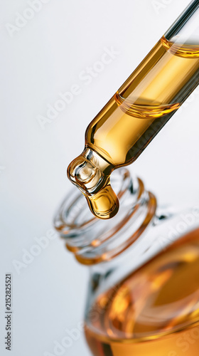 Golden serum dropper releasing liquid into bottle close up, capturing rich texture and clarity with soft lighting for clean, fresh skincare concept