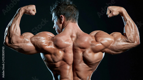 Muscular Back Pose: A powerfully built male bodybuilder flexes his impressive back muscles in a dramatic pose, showcasing incredible strength and definition.