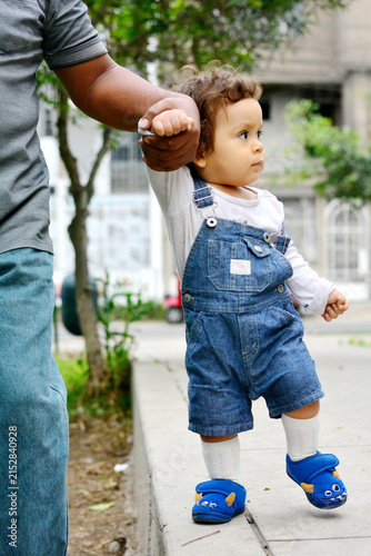 Daddy and his toddler son walking in the street.