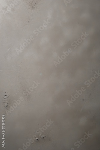 Close-up of textured gray plaster wall with subtle pinkish tones, uneven surface, and soft shadows, highlighting natural imperfections and rustic detail.