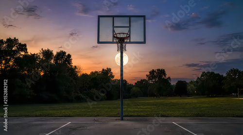 Basketball hoop on an outdoor court at sunset with full moon illustration