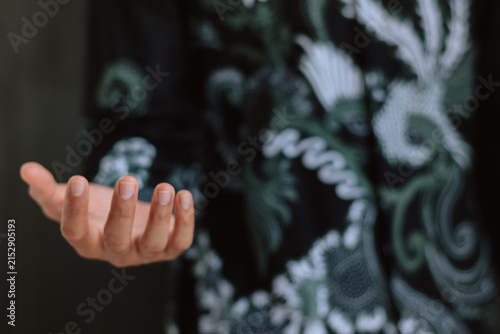 Photography Close up of hand in batik shirt open palm gesture representing traditional found