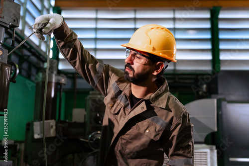Фотография Professional male technician cleaning heavy machinery with air blow gun in facto