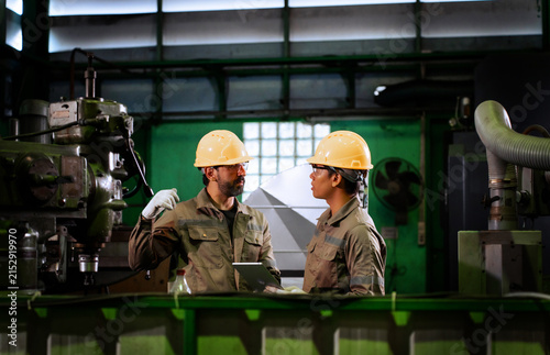 Фотография Two industrial technicians inspect metal component precision and discuss quality