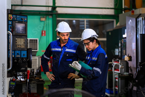 фотографія Industrial engineers inspecting cnc machine operation with clipboard in modern factory