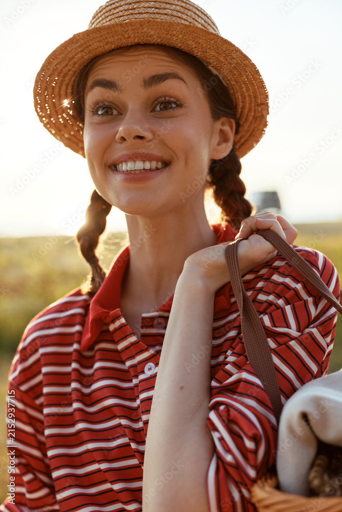 Obraz premium Young woman with braided hair wearing a straw hat and striped shirt outdoor. Lifestyle portrait happy female enjoying nature sunny day concept for summer recreation.